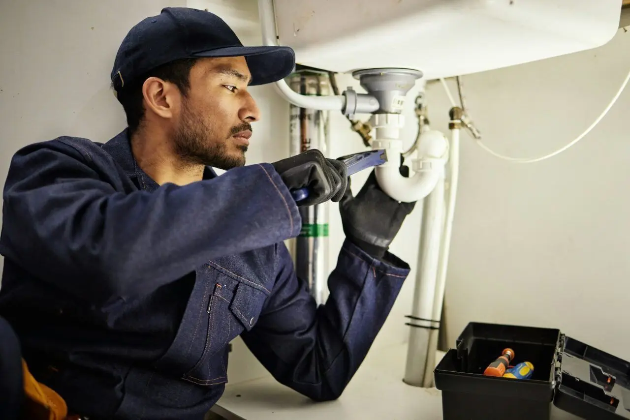 Licensed Sunshine Coast plumber repairing kitchen pipes during a residential plumbing inspection