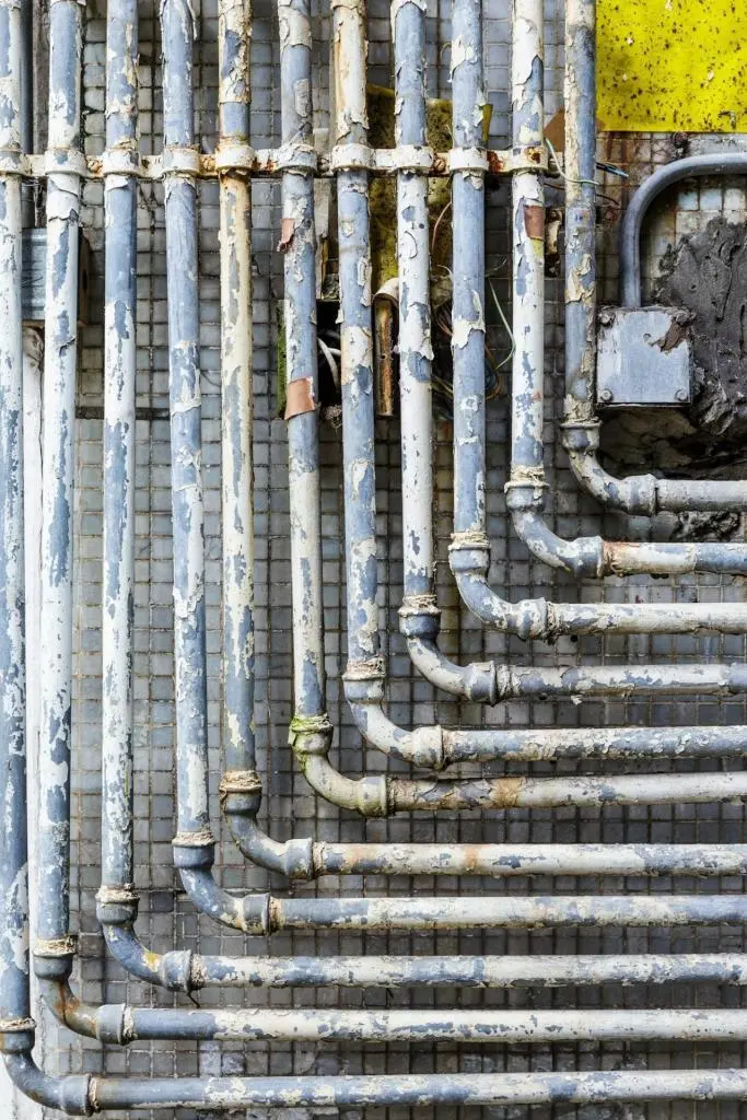 Old parallel pipes mounted on a wall, showcasing plumbing infrastructure